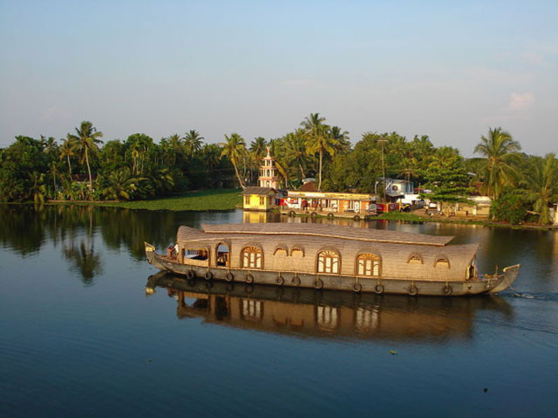 Houseboat on the backwater near the temple with background of coconut palm, Kerala, traditional.
