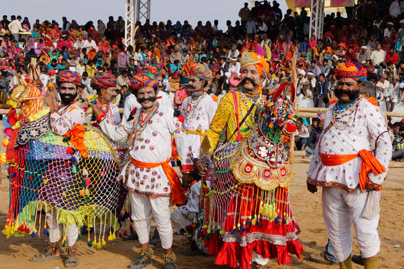 Pushkar Men in ornate traditional costumes with decorative waistbands performing at Rajasthan festival