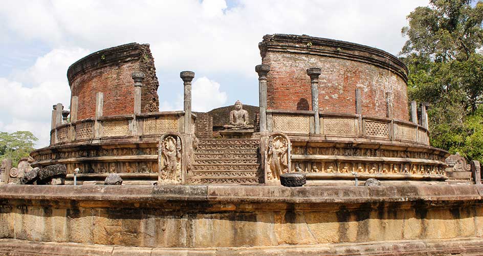 Ancient circular brick ruins with columns on stone platform at archaeological site