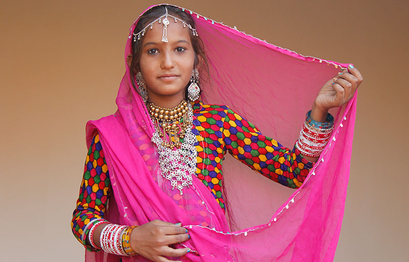 Young woman in pink veil and colorful polka-dot outfit with traditional silver jewelry