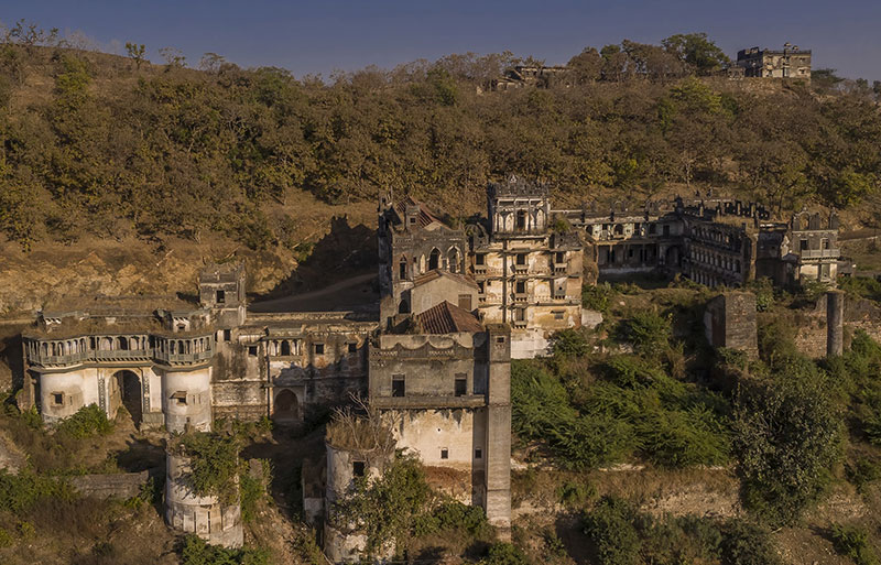 Abandoned historic fort complex on hillside surrounded by dry forest landscape