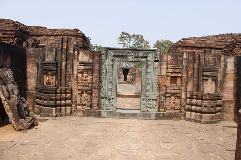 Old temple door of excessively decorated stone carvings and aged brick walls.